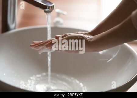 Young woman washing hands over bathroom sink, close up view Stock Photo