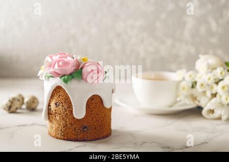 Easter breakfast. Homemade cake with flowing down cream and pink roses on marble table. Cup of tea with flowers. Holiday concept Stock Photo