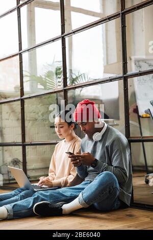 Photo of a young serious colleagues indoors work in office with laptop computer using mobile phone. Stock Photo