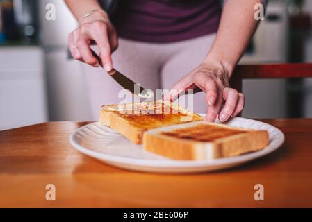 two hands spreading butter on toast Stock Photo