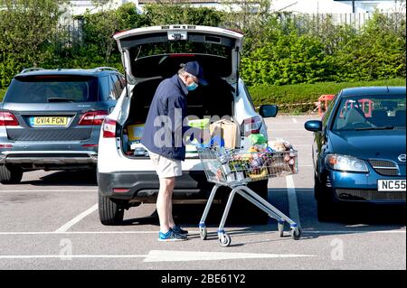 Tesco Supermarket, Hove, U.K., 2020. An elderly man unloads his shopping wearing a face mask for safety in the wake of the coronavirus pandemic. Stock Photo