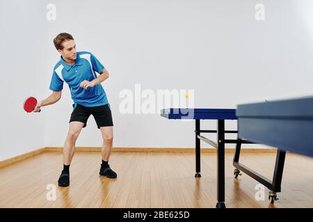 Table tennis player hitting ball when playing after work Stock Photo