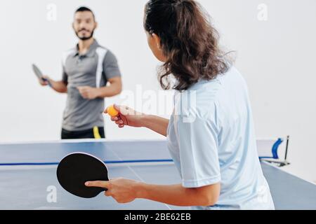 Woman serving ping pong ball when playing table tennis with her friend after work Stock Photo