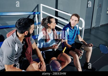 Badminton players resting on bench, drinking water and discussing strategy after game Stock Photo