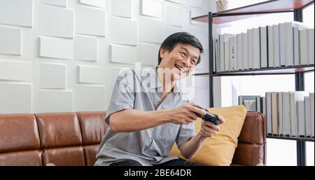Senior Asian man using tablet and virtual reality simulator playing games in living room and feeling happy . Lifestyle Senior family at home concept. Stock Photo