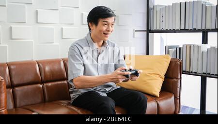 Senior Asian man using tablet and virtual reality simulator playing games in living room and feeling happy . Lifestyle Senior family at home concept. Stock Photo