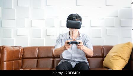 Senior Asian man using tablet and virtual reality simulator playing games in living room and feeling happy . Lifestyle Senior family at home concept. Stock Photo