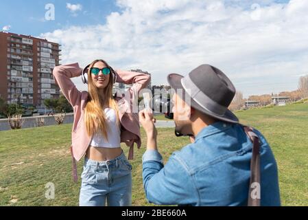 Photographer conducts a photo shoot of a young Caucasian girl outdoors in a city park Stock Photo