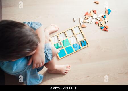 Sad boy sitting on floor with unsolved puzzle. Top point of view. Concept of failure Stock Photo