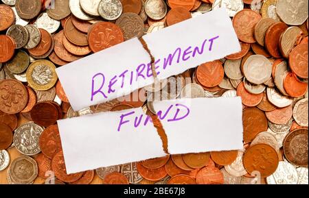 The words retirement fund written in purple pen on white paper, the paper is ripped across the words retirement fund the paper is on top of hundreds o Stock Photo