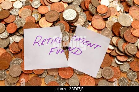 The words retirement fund written in purple pen on white paper, the paper is ripped across the words retirement fund the paper is on top of hundreds o Stock Photo