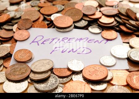 The words retirement fund written in purple pen on white paper, the paper is on top of hundreds of silver and copper coloured British coins Stock Photo