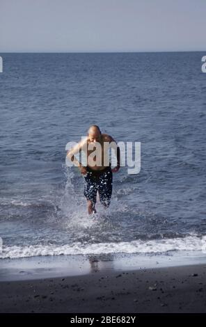 A man in swimming trunks  bravely takes a dip in the Arctic Ocean on a summer day in Barrow, Alaska, USA Stock Photo