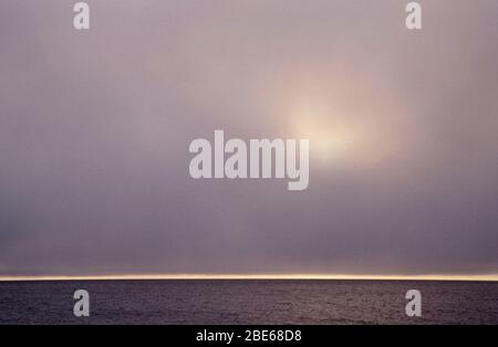 Diffuse sun shining through clouds at midnight over the sea in the Land of the Midnight Sun, Barrow, Alaska, USA Stock Photo