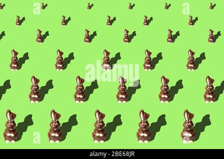 Easter bunny shaped sweets of milk chocolate laying in rows on light green background. Religious holiday composition,rabbit pattern for congratulation Stock Photo
