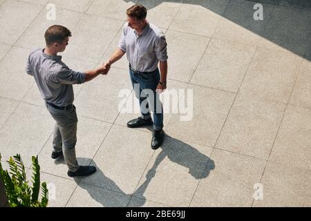 Young confident business people standing outdoors and shaking hands after meeting Stock Photo