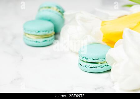 Macaroons closeup with white and yellow flowers on marble table. Mother's day concept Stock Photo