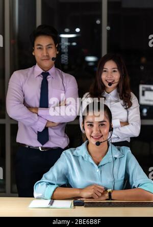Late Night Environment, Potrait of friendly Call centre operator team with headsets in a call center customer service and technical support. Using for Stock Photo