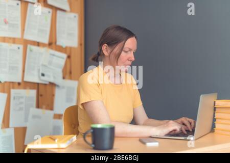 Female freelancer working from home on laptop computer, woman telecommuting from home office, selective focus Stock Photo