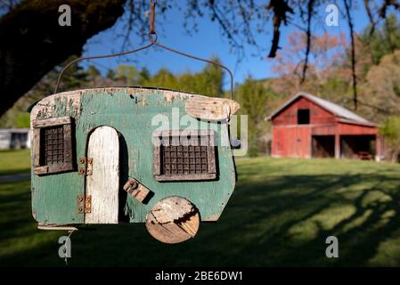 Retro wooden camper trailer birdhouse with red barn in the background - Penrose, North Carolina, USA Stock Photo