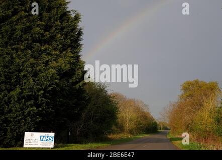 Hoton, Leicestershire, UK. 12th April 2020.  A rainbow begins to form over a sign thanking the NHS and frontline workers in Hoton during the Coronavirus pandemic lockdown. Credit Darren Staples/Alamy Live News. Stock Photo