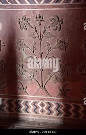 Dawn light illuminates a sandstone floral spray relief inside the Taj Mahal symbolising a paradise theme, framed inside stone inlay borders, India. Stock Photo