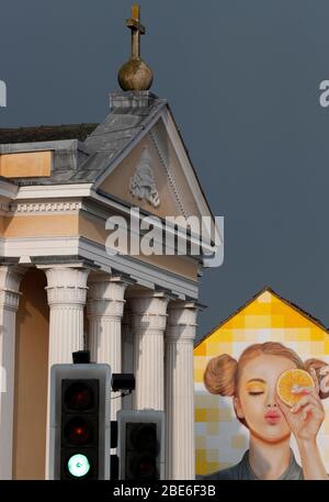 St Mary's Catholic church stands in front of a building painted with street art on Ashby Road in Loughborough, Leicestershire, UK. 12th April 2020. Stock Photo