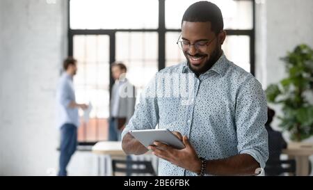 Happy african American male employee use tablet in office Stock Photo