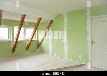 Home renovation work in progress. Repairing old green wall cracks in wall with white new putty. Home renovations concept. Stock Photo