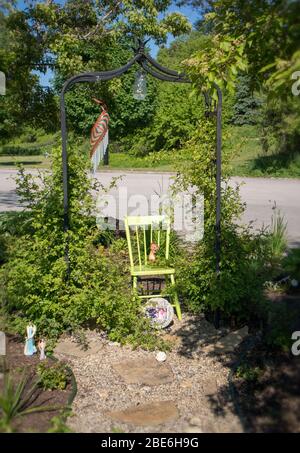 In a garden made in memory of those we loved and passed away, a chair of the defunct surrounded by plants. Stock Photo