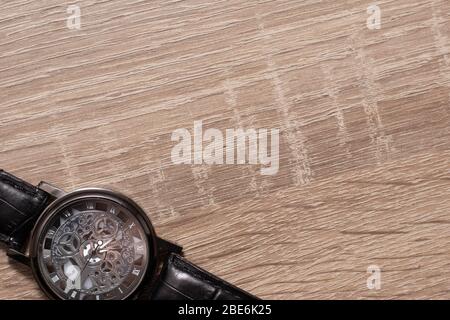 Simple metal silver retro wristwatch with a black belt on a grey wooden background. Stock Photo