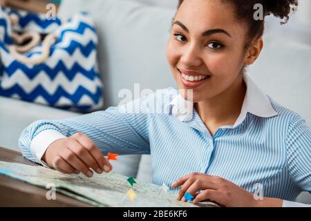 Tour agent sitting at table in office marking places on map smiling happy Stock Photo