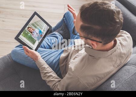 Man connects with doctor by pc tablet in the internet, while sitting at home. View from above. Online consultation Stock Photo