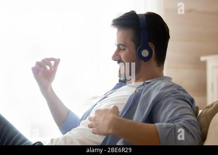 Cheerful young man listening to energetic music in wireless headphones. Stock Photo