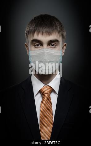 concept coronavirus epidemic, portrait businessman in medical mask, black costume and orange necktie, face closeup, Stock Photo