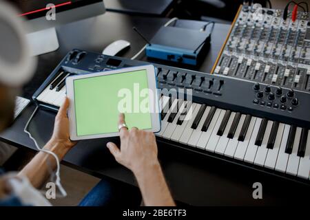 Sound engineer is working at mixing panel in the recording studio and holding a tablet pc. Close-up concept. There is mixer, operating the leader. Stock Photo