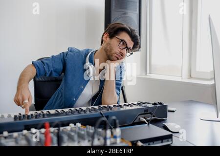 No mood and inspiration. Very boring. Male music arranger hands composing song on midi piano and audio equipment in digital recording studio. Man Stock Photo