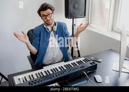 He looks into the camera and shrugs his hands. He is bewildered and does not know what to do. Bad employee. Male music arranger composing song on Stock Photo