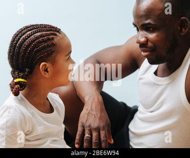 Father and daughter looking into each other's eyes over blue Stock Photo