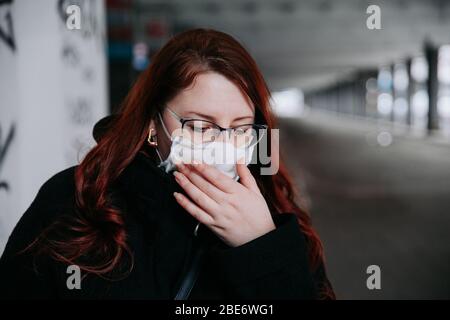 Woman feeling unwell and wearing face mask in city Stock Photo