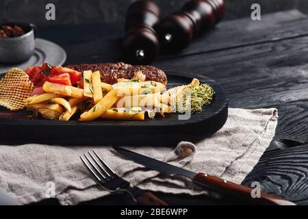 Kebab with french fries, chips and fresh tomatoes, served on a wooden plate. Food photo, traditional Caucasian cuisine. Stock Photo