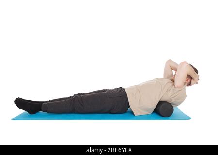 Handsome man shows exercises using a foam roller for a myofascial release massage of trigger points. Massage of the lower back muscle. Isolated on whi Stock Photo