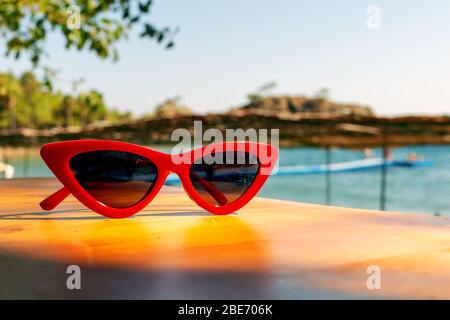 Red Cat's Eye Sunglasses on a wood table in the beach and a sea view on the background. Stock Photo