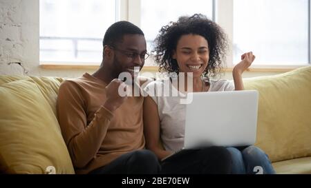 Happy young african american couple looking at laptop. Stock Photo