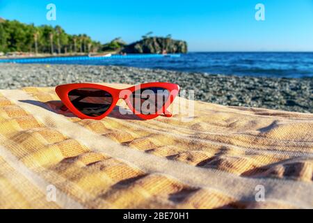 Black Cat's Eye Sunglasses on a towel in the beach and a sea view on the background. Stock Photo