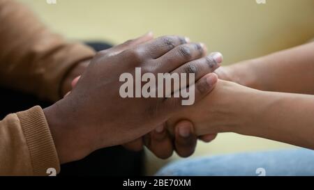 Close up african american man hands holding upset depressed woman. Stock Photo