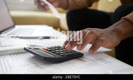 Close up black man hand using calculator and laptop. Stock Photo