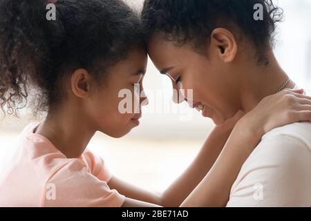 Close up happy african american daughter touching forehead with mother.