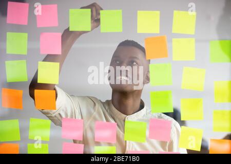 Smiling biracial man write on colorful notes developing startup Stock Photo