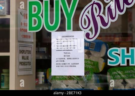 A social distancing, and wear mask safety sign taped to a window at a store in Manhattan Chinatown in New York during coronavirus COVID-19 pandemic. Stock Photo